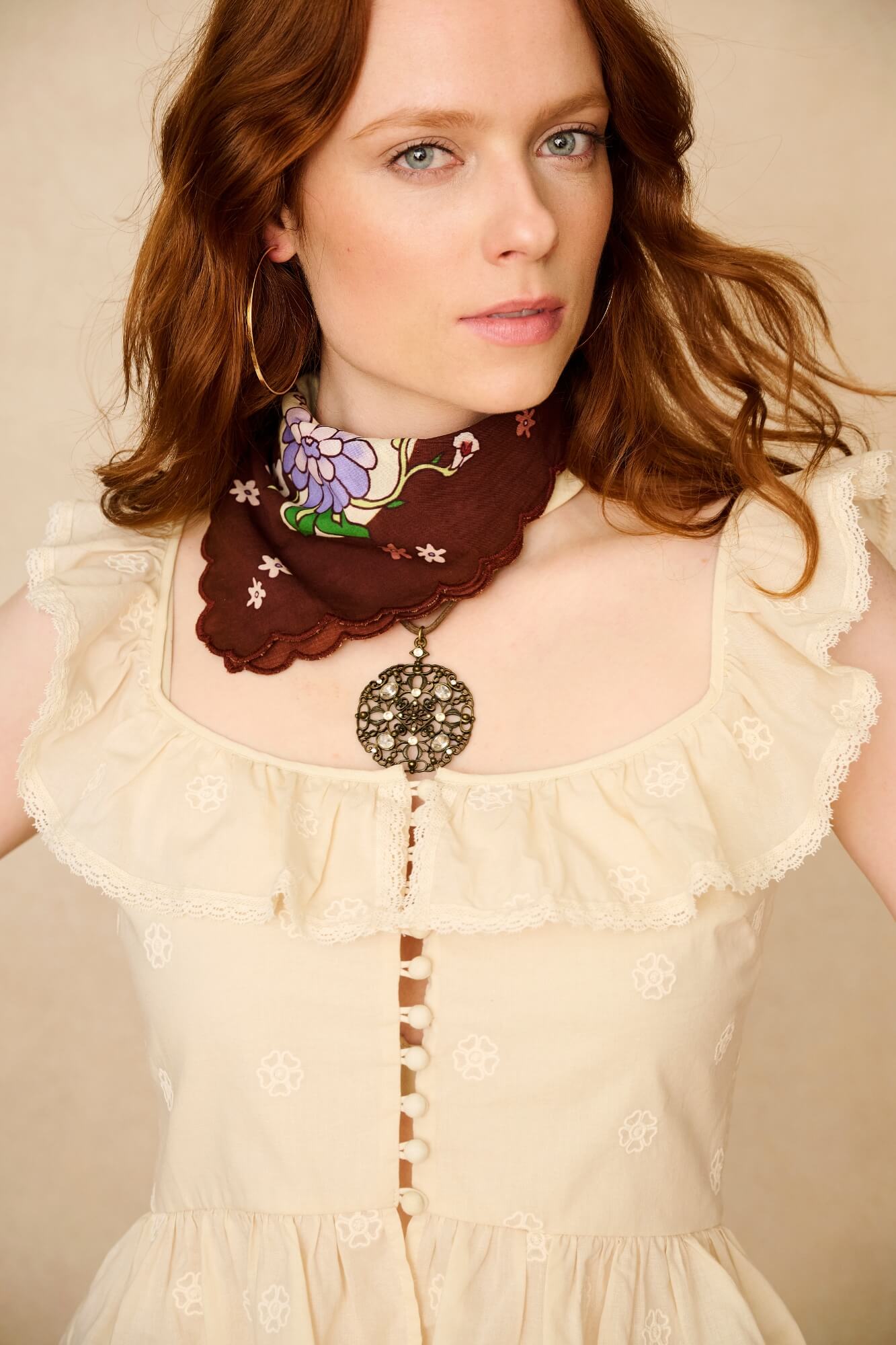 Woman wearing a decorative scarf and necklace against a plain background