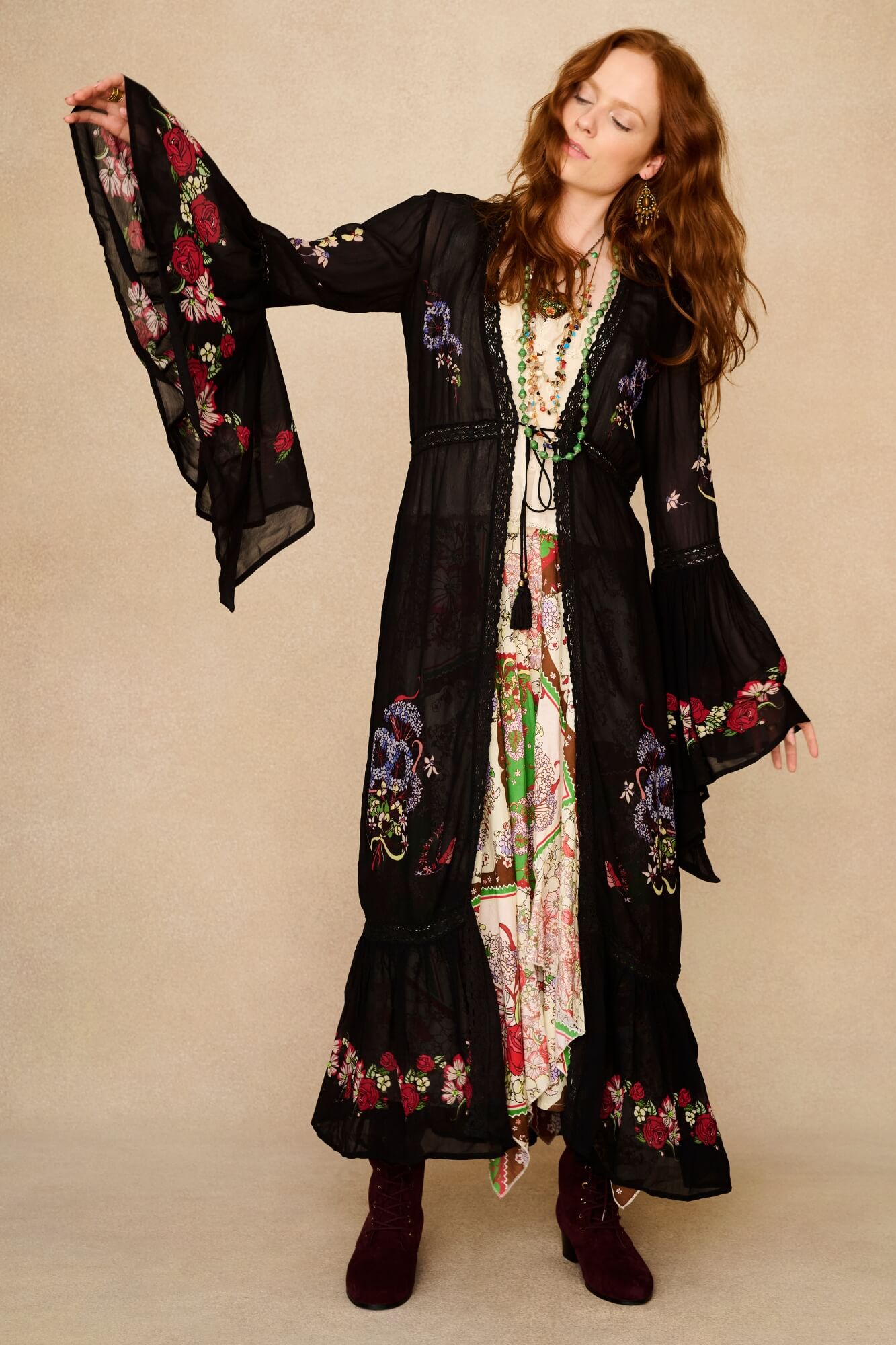 Woman wearing a black embroidered duster with floral patterns on a beige background