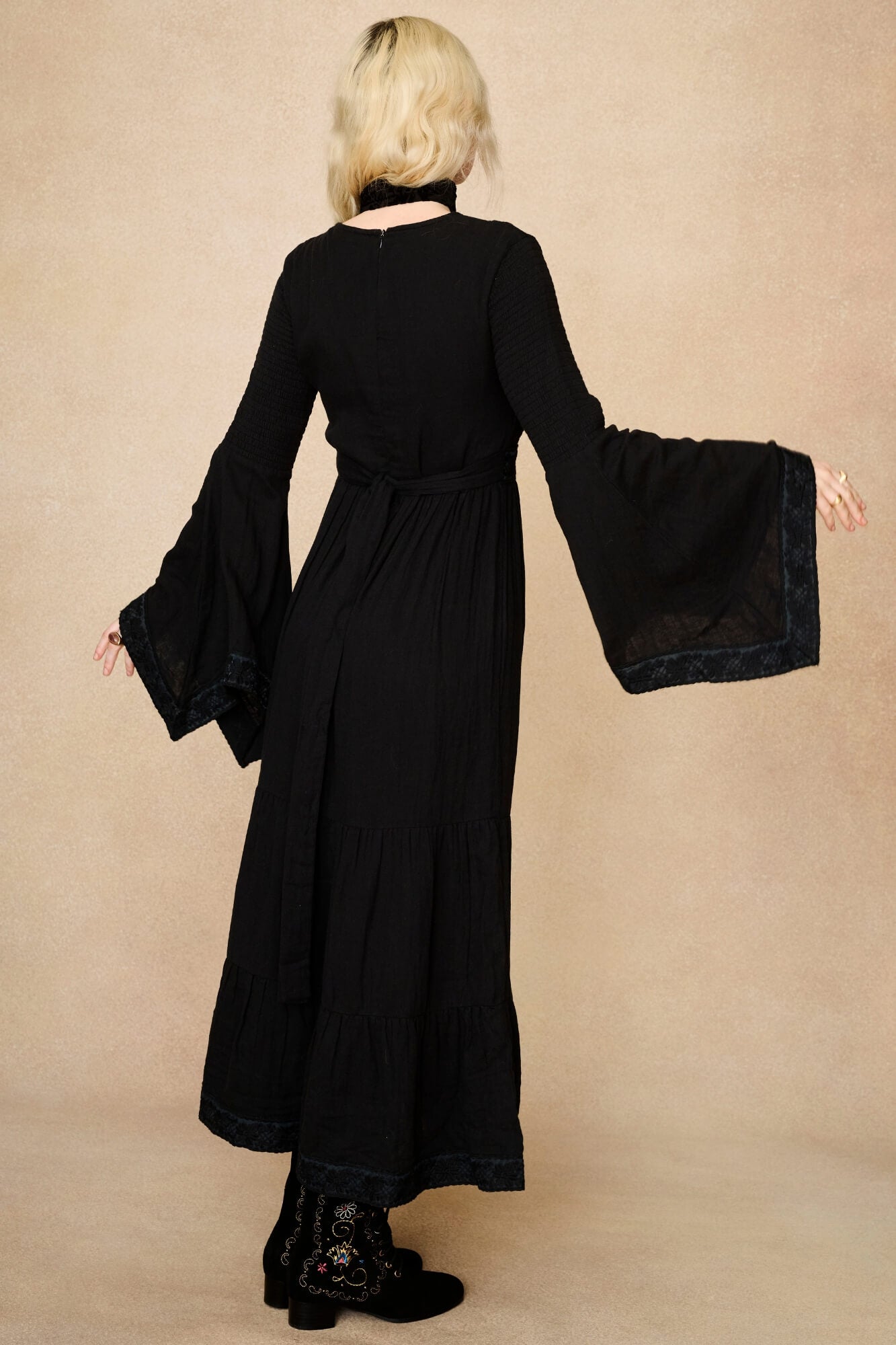 Model wearing 70s black long sleeve maxi dress with lace-up Penny Lane boots by The Hippie Shake, back view