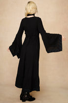 Model wearing 70s black long sleeve maxi dress with lace-up Penny Lane boots by The Hippie Shake, back view