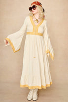Model wearing 70s cream long sleeve maxi dress with lace-up Penny Lane boots by The Hippie Shake, front view