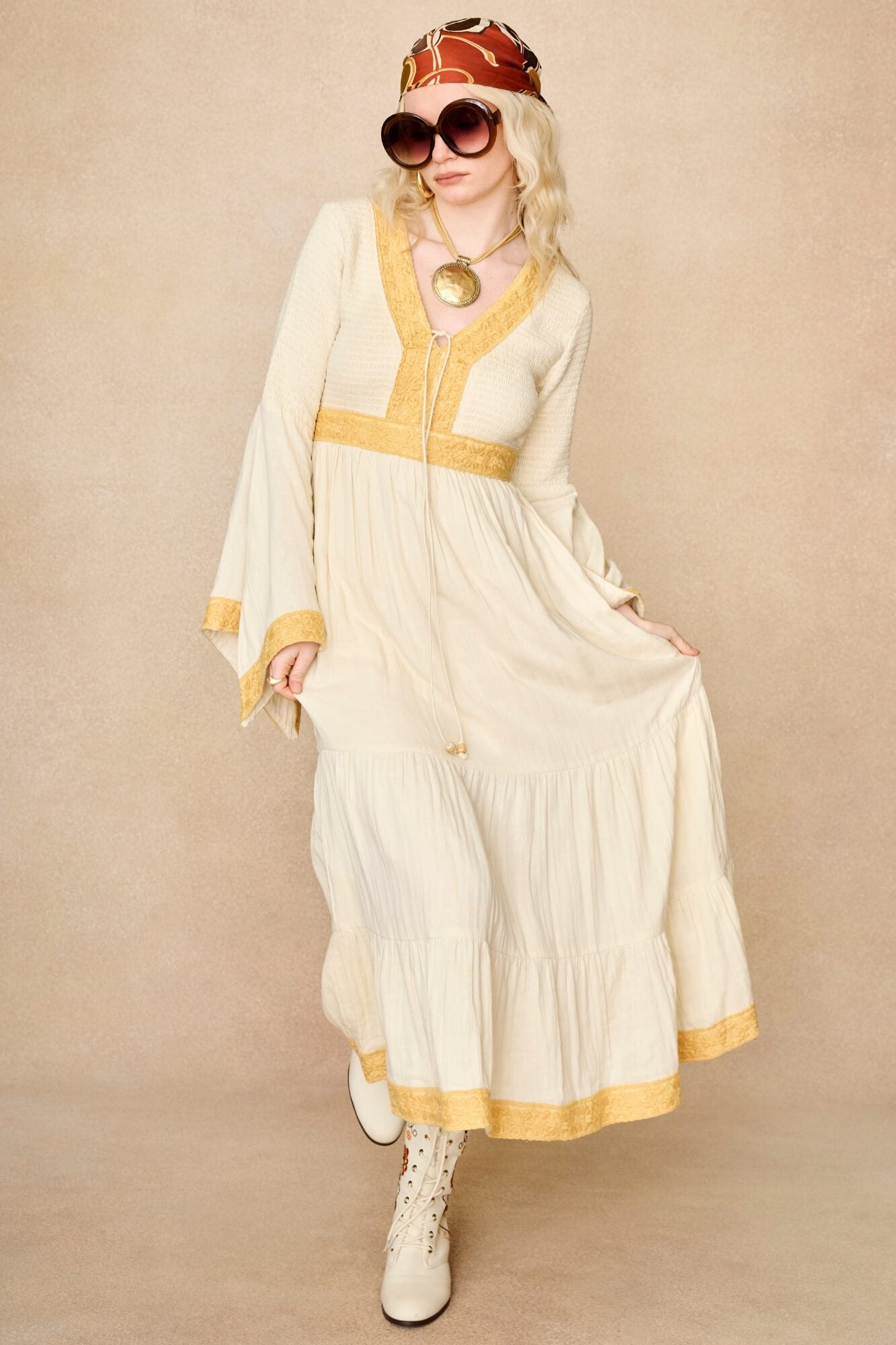 Model wearing 70s cream long sleeve maxi dress with lace-up Penny Lane boots by The Hippie Shake, front view