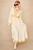 Model wearing 70s cream long sleeve maxi dress with lace-up Penny Lane boots by The Hippie Shake, front view