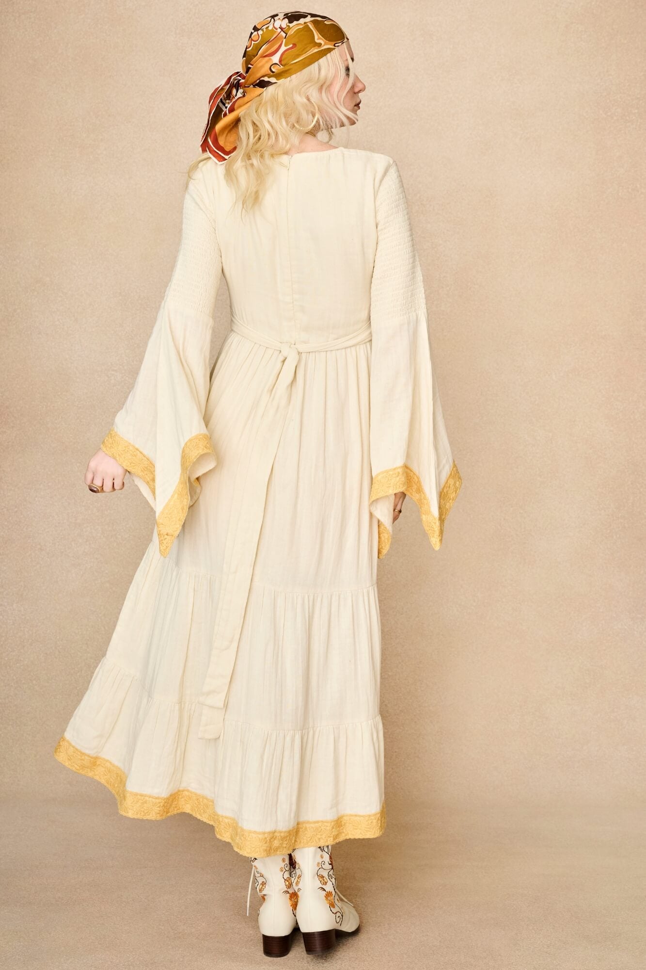 Model wearing 70s cream long sleeve maxi dress with lace-up Penny Lane boots by The Hippie Shake, back view