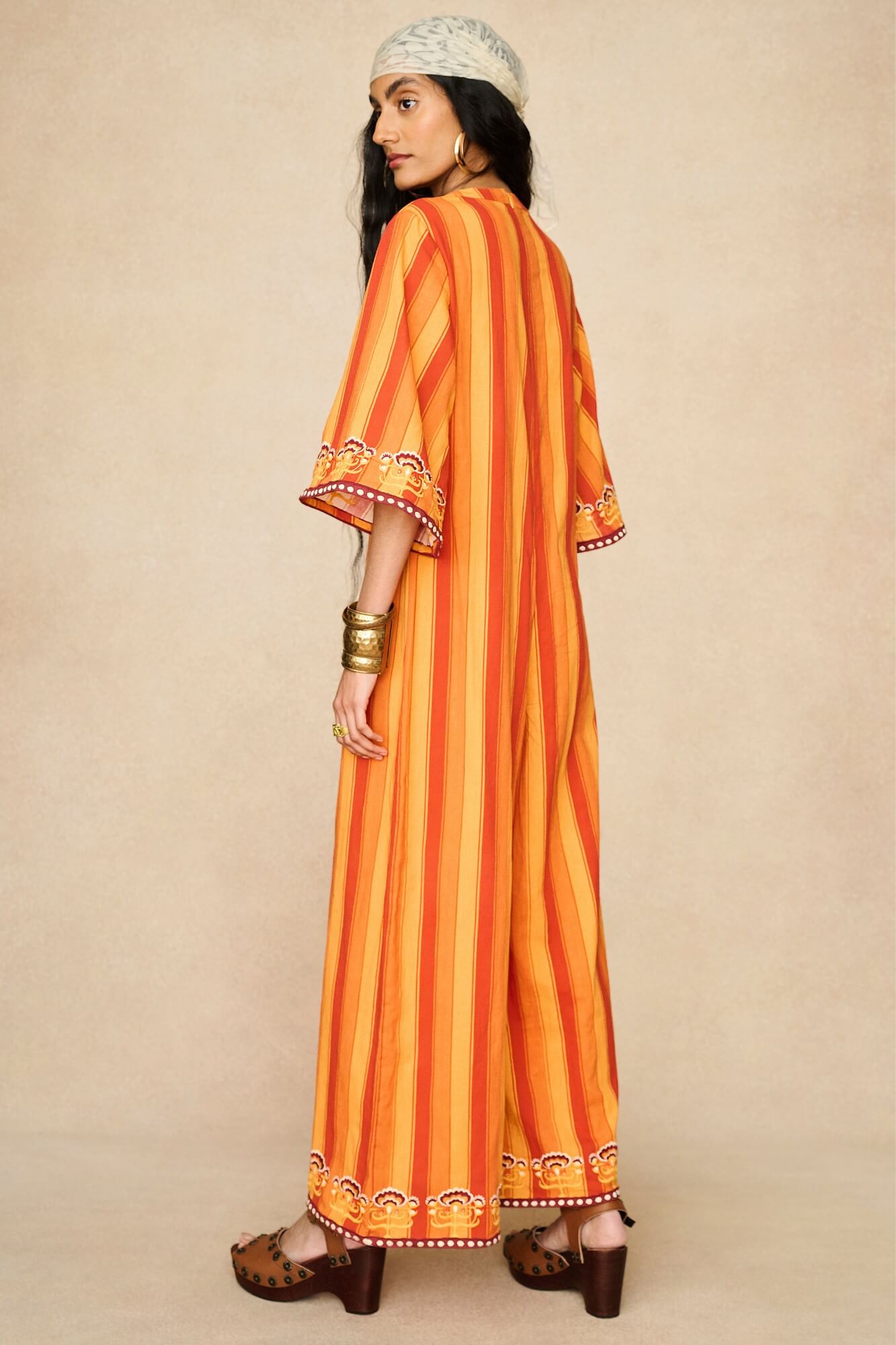 Model wearing 70s orange striped wide leg jumpsuit by The Hippie Shake, back view