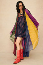Model wearing 70s striped mini dress styled with a rainbow cape by The Hippie Shake, front view